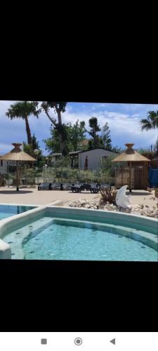 une grande piscine devant un complexe hôtelier dans l'établissement les sables du midi mobil home bougainvilliers, à Sérignan