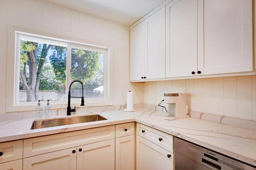 a kitchen with white cabinets and a sink and a window at A Cozy Home | Games | Dogs OK in Yuba City