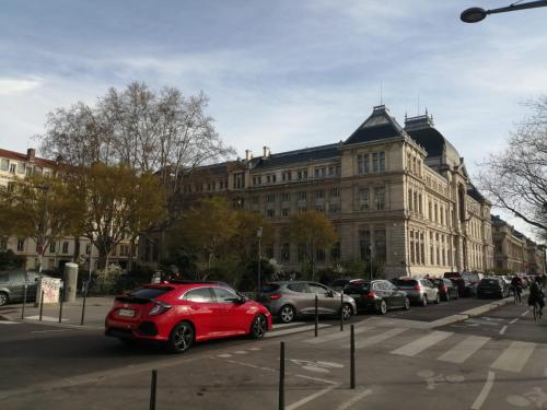 une voiture rouge garée devant un grand bâtiment dans l'établissement Loft ViaRhôna, Grand loft en Centre-Ville, à Lyon