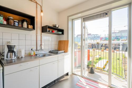 a kitchen with white cabinets and a large window at Apartment Hotel Zuid Oost Heesterveld BnB ZOH in Amsterdam