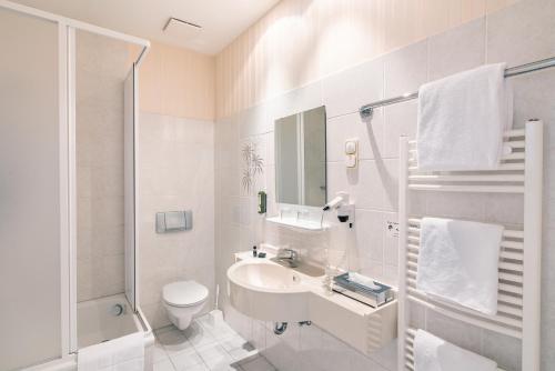 a bathroom with a sink and a toilet and a shower at SEETELHOTEL Villa Möve in Heringsdorf