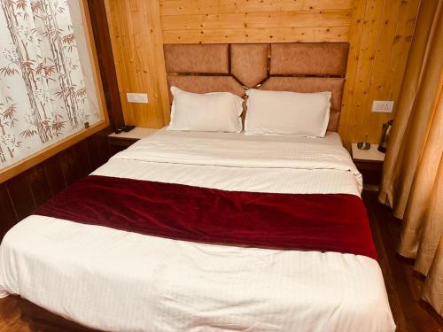 a large bed in a room with wooden walls at Oak View - A Pine Tree Resort in Shimla