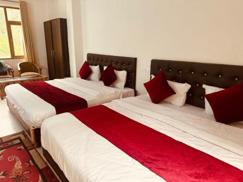 two beds in a hotel room with red pillows at Oak View - A Pine Tree Resort in Shimla