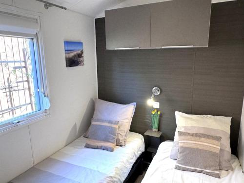 une petite chambre avec deux lits et une fenêtre dans l'établissement Sous les pins du Bassin - Mobile Home avec jardin, à La Teste-de-Buch