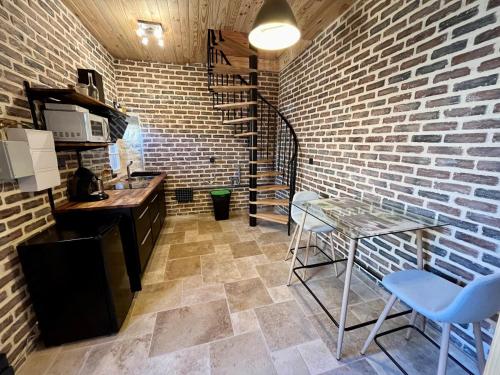 une cuisine avec une table et un mur en briques dans l'établissement Little cottage with garden in Chatellerault, à Châtellerault