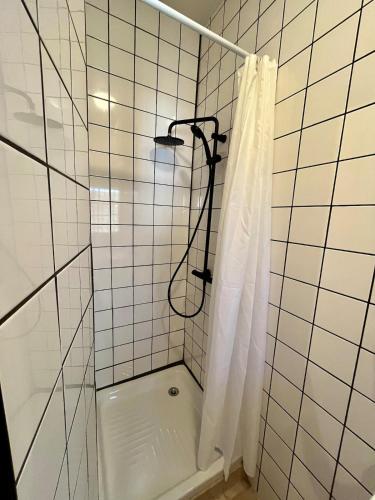 La salle de bains carrelée de blanc est pourvue d'une douche et d'un rideau de douche. dans l'établissement Little cottage with garden in Chatellerault, à Châtellerault