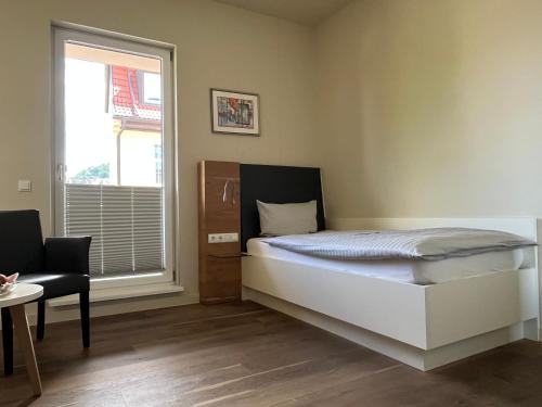 a bedroom with a bed and a window and a chair at Gasthaus Zur Noll in Jena