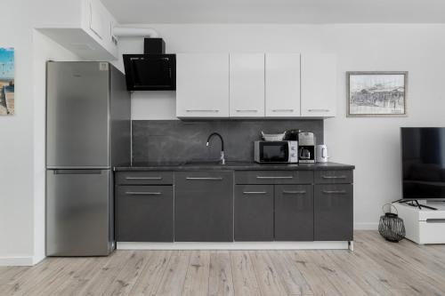 a kitchen with a stainless steel refrigerator and white cabinets at Balticus by Solarento in Międzyzdroje
