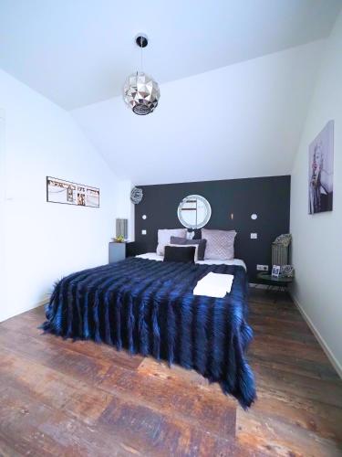 a bedroom with a large bed with a blue blanket at La Marilyn by Leslodgespa - Confort haut de gamme, salle de bain privée, jardin et cuisine commune, à 5 minutes de l'aéroport in Blotzheim