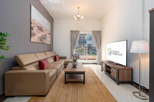 a living room with a couch and a tv at BLVD - Spacious Fully Equipped Luxury Residences - Dubai - JVC in Dubai