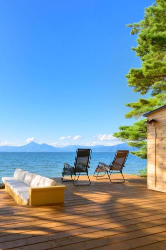 two chairs and a couch on a deck with the water at Lakehide Konan - 湖畔の貸別荘 - サウナ使い放題 - 1棟貸切 in Koriyama