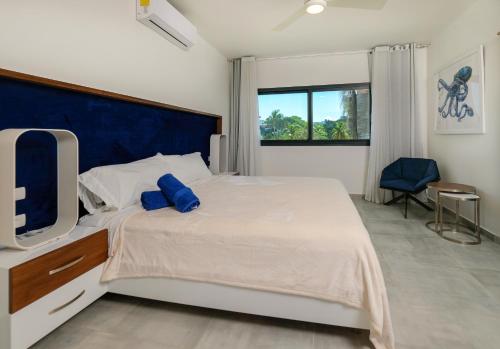 a bedroom with a bed with a blue headboard and a tv at Stella Aparthotel, Las Terrenas in Las Terrenas
