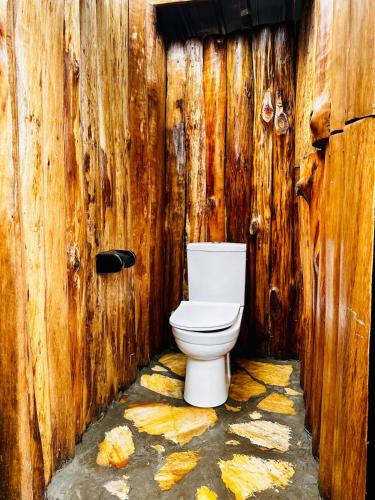 a bathroom with a toilet in a wooden wall at Kasana Lake House in Isunga