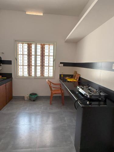 an empty kitchen with a stove and a table at SRI Villa Rooms in Wayanad - Family Villa Stay with Mountain views in Vayittiri