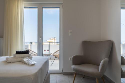 a bedroom with a bed and a chair and a balcony at Horizon Luxury Living Breathtaking Seaview Minutes from the Airport in Artemida