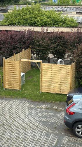 a wooden fence in the grass next to a car at Alinas Ferienwohnung Güstrow in Güstrow