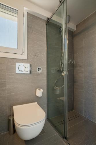 a bathroom with a toilet and a glass shower at Horizon Luxury Living Breathtaking Seaview Minutes from the Airport in Artemida