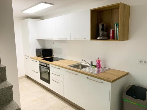 une cuisine avec des armoires blanches et un évier dans l'établissement Maison avec garage - à 5 min du centre-ville, à Strasbourg
