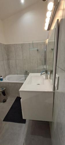a white bathroom with a sink and a tub at Location Le Tilleul in Pélissanne