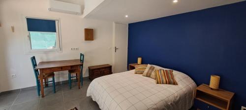 a bedroom with a bed and a desk and a blue wall at Location Le Tilleul in Pélissanne