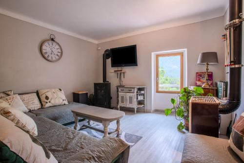 a living room with a couch and a clock on the wall at Appart Authentique et Confortable in Valderoure