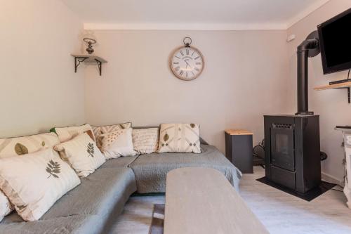 a living room with a couch and a clock on the wall at Appart Authentique et Confortable in Valderoure