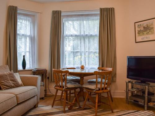 Una sala de estar con una mesa y sillas y un televisor. en Steephill Lodge, en Saint Lawrence