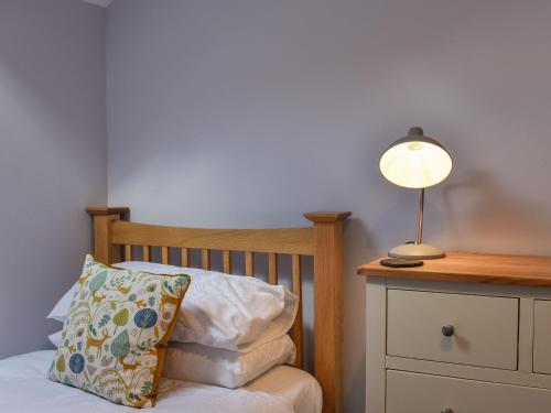 a bed with a pillow and a lamp on a dresser at Ted's Place in Arnside