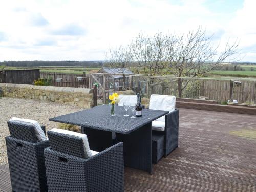 a black table with chairs and flowers on a deck at The Cockles in Ulgham