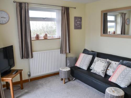 a living room with a black couch and a window at The Cockles in Ulgham