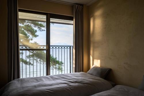a bedroom with a bed in front of a window at Lakehide Konan - 湖畔の貸別荘 - サウナ使い放題 - 1棟貸切 in Koriyama