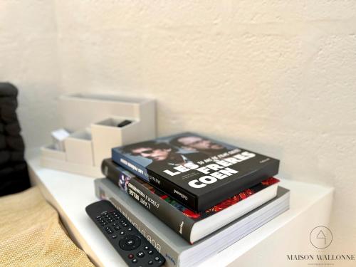 a stack of books on a shelf with a remote control at Le Tipi - Sauna et Jardin in Esneux
