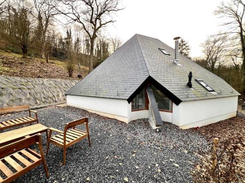 a small white building with a roof and two benches at Le Tipi - Sauna et Jardin in Esneux