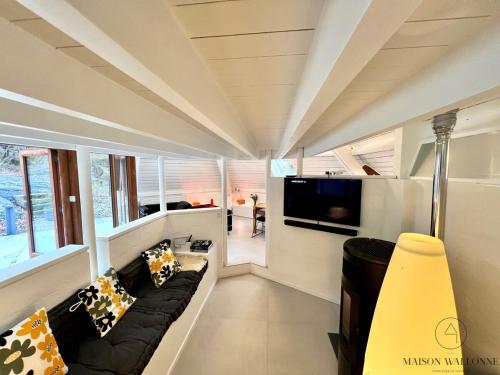a living room with a couch and a tv at Le Tipi - Sauna et Jardin in Esneux