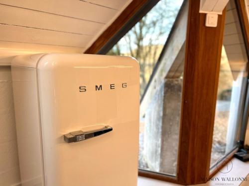 a white refrigerator in front of a window at Le Tipi - Sauna et Jardin in Esneux