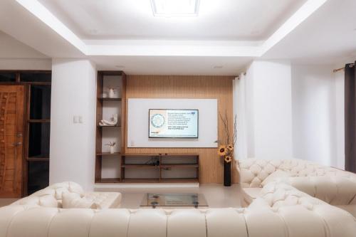 a living room with two white couches and a tv at MG Transient House in Baguio