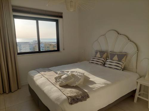 a bedroom with a white bed with a window at Lindo T2 com vista mar in Quarteira