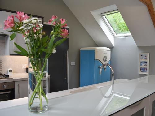 a vase of flowers on a counter in a kitchen at Priory Barn in Freshwater