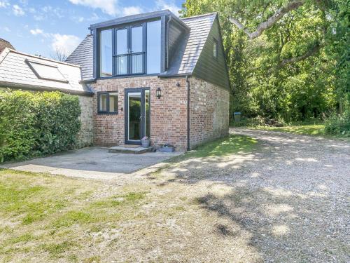 Una casa de ladrillo con una ventana encima. en South Wood Lodge, en Slindon