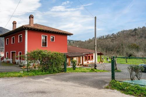 a red house with a fence in front of it at Apartamentos Les Cuartes in Cangas de Onís