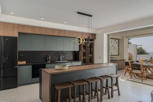 a kitchen with a bar with stools in it at Luxurious Villa Selestine - With Private Pool in Panormos Rethymno