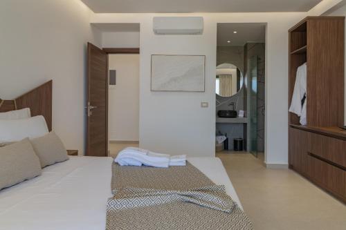 a bedroom with a white bed and a mirror at Luxurious Villa Selestine - With Private Pool in Panormos Rethymno