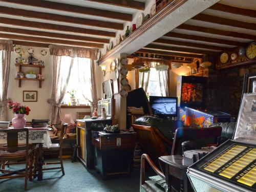 un soggiorno con pianoforte, tavolo e sedie di Chapel Cottage a Pont Sticill