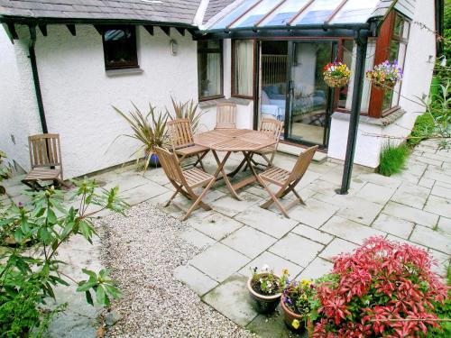 a patio with a table and chairs and some plants at Bank End in Glenridding