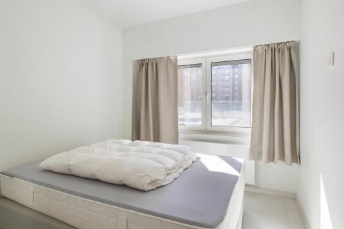 a bed in a white room with a window at Zeewind 0101 in Oostduinkerke