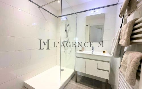 une salle de bain blanche avec une douche et un lavabo dans l'établissement Appartement Petru Paisible & spacieux, à Calvi