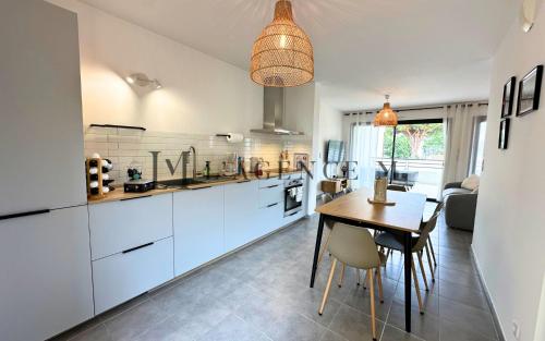 une cuisine avec des armoires blanches et une table avec des chaises dans l'établissement Appartement Petru Paisible & spacieux, à Calvi