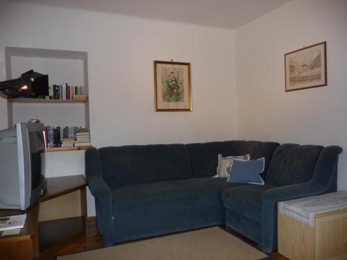 a living room with a blue couch and a tv at Landhaus Fiausch in Mallnitz