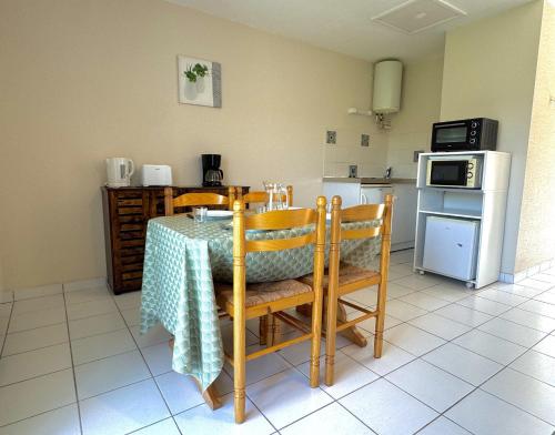 a kitchen with a table and chairs and a kitchen with a stove at La Vallée Appartement 35 - Thermes Neyras les Bains in Meyras