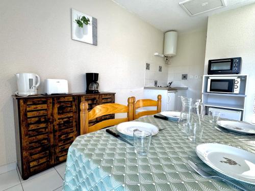 a kitchen with a table with plates on it at La Vallée Appartement 35 - Thermes Neyras les Bains in Meyras